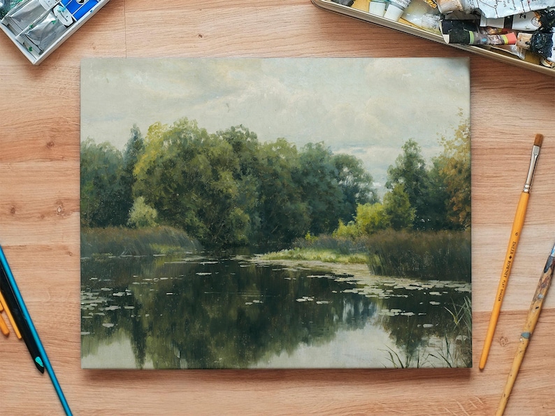 An oil painting depicting a tranquil landscape scene. The artwork showcases a serene lake reflecting lush green trees and foliage under a cloudy sky. Paintbrushes and art supplies surround the painting, suggesting an artist's workspace.