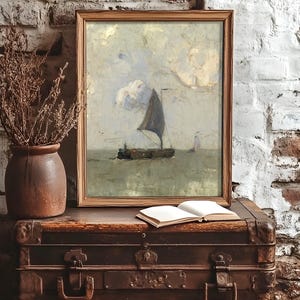 Framed artwork of a sailboat on calm waters rests on a vintage trunk. Nearby, a clay vase with dried branches and an open notebook create a rustic ambiance.