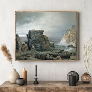 Framed seascape painting on a wall above a wooden shelf. The scene shows rugged cliffs and waves, with decor items like vases and candles below.