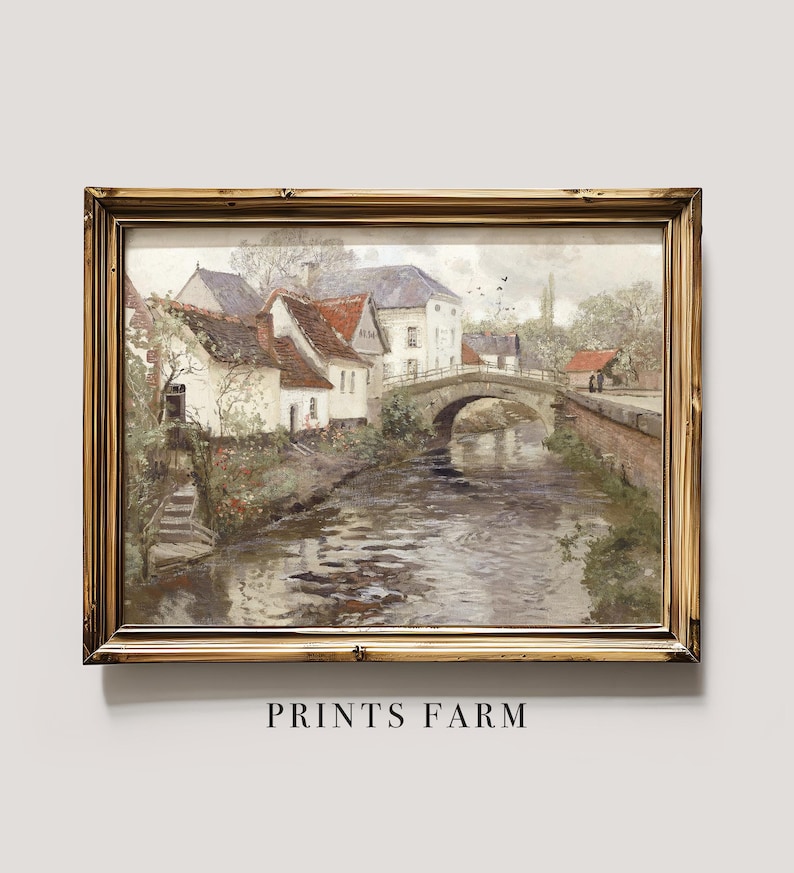 Framed painting of a serene village scene featuring rustic houses by a river, a stone bridge, and figures walking. The mood is tranquil and picturesque.