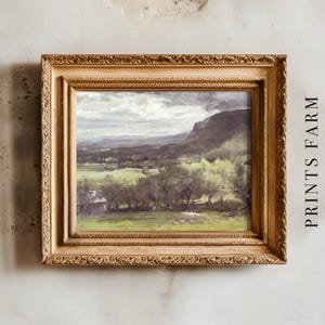 Framed landscape painting on a textured wall, featuring lush green fields and distant mountains under a cloudy sky. Text "PRINTS FARM" on the side.