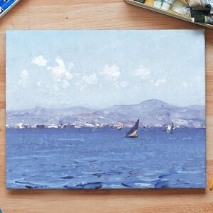 A painting of a sailboat on a serene blue sea with distant mountains and fluffy clouds. Surrounding are art supplies on a wooden table, creating a calm and creative atmosphere.