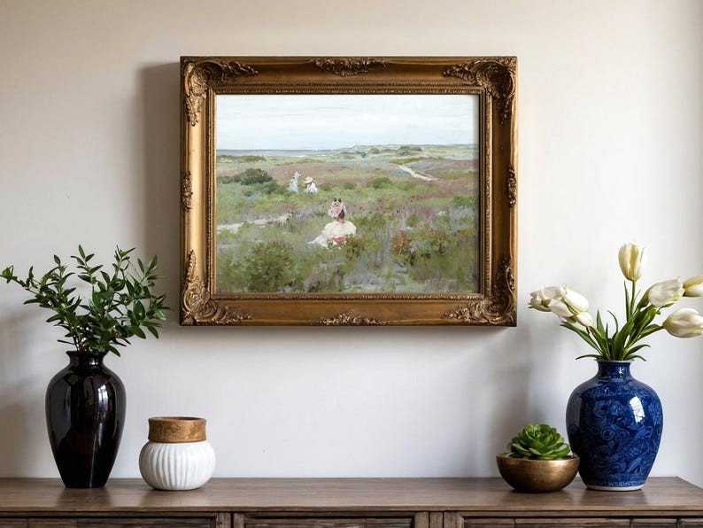 A landscape painting in an ornate gold frame hangs on a beige wall. Flanking it are vases with plants, including tulips and green foliage, on a wooden cabinet.
