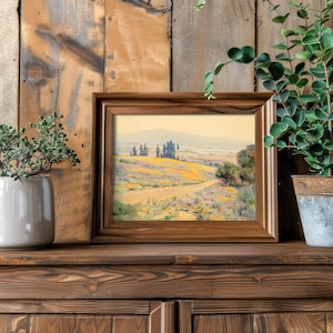 Framed landscape painting on wooden shelf, flanked by two potted plants. Rustic, natural vibe with a serene, artistic atmosphere.