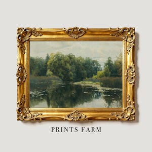 A framed painting of a serene lake with lily pads framed by lush green trees. The ornate golden frame adds an elegant touch to the peaceful scene.