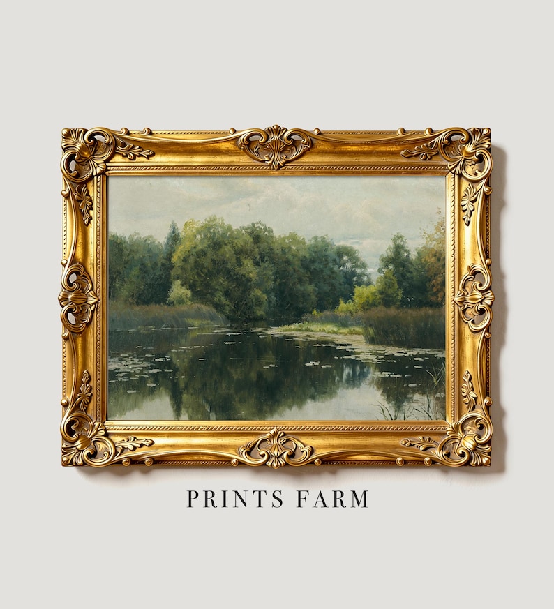 A framed painting of a serene lake with lily pads framed by lush green trees. The ornate golden frame adds an elegant touch to the peaceful scene.