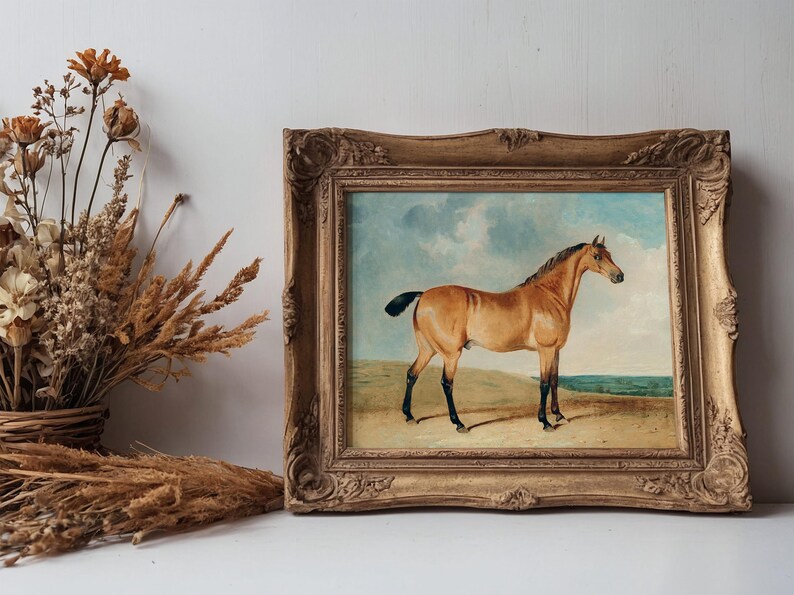 A vintage gold-framed painting of a horse on a sandy landscape is displayed on a shelf. Beside it, a rustic basket holds dried wildflowers.
