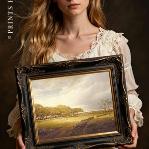A woman in a lace dress holds an ornate framed landscape painting depicting trees and a cloudy sky. The mood is serene and classic.