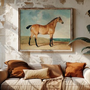 Cozy living room with a white sofa and rust-colored pillows beneath a horse painting. Rustic wall texture and lush plants add warmth and charm.