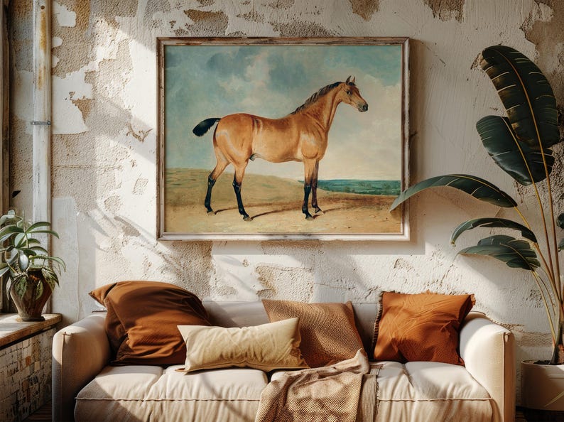 Cozy living room with a white sofa and rust-colored pillows beneath a horse painting. Rustic wall texture and lush plants add warmth and charm.