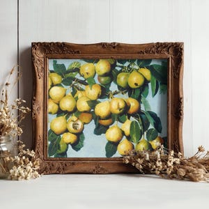 Ornate wood-framed painting of yellow apples on branches, set against a white wooden wall. Flanked by jars of dried flowers, creating a rustic, artistic vibe.