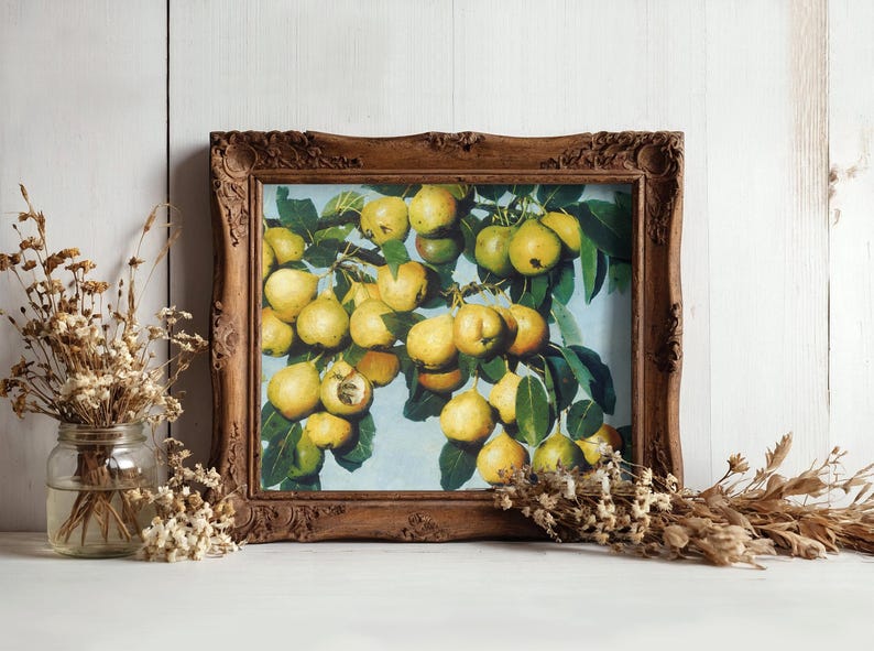 Ornate wood-framed painting of yellow apples on branches, set against a white wooden wall. Flanked by jars of dried flowers, creating a rustic, artistic vibe.