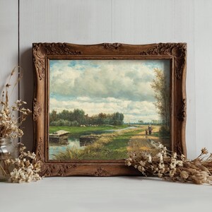 A framed landscape painting shows a serene riverside path under a cloudy sky, with two figures walking. Dried flowers in jars sit beside it, adding rustic charm.
