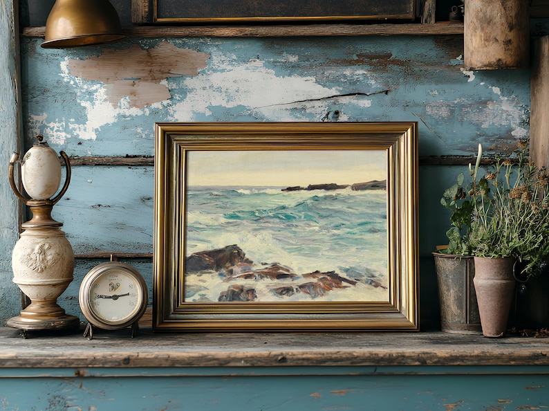A coastal painting in a gold frame rests on a rustic shelf. Beside it, an antique lamp and clock sit on worn, peeling blue wood, while potted plants add greenery.