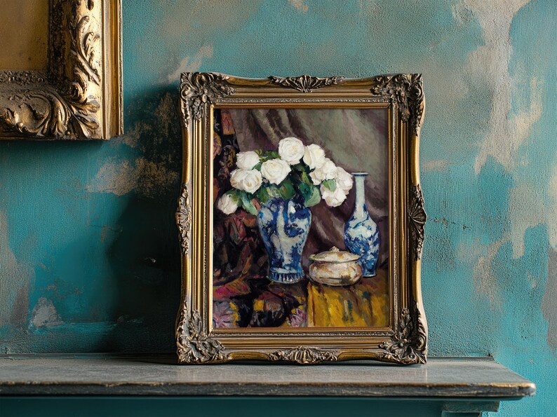 Framed painting of white roses in a blue vase on a textured teal wall. The ornate, gold frame complements the rustic and vintage ambiance.
