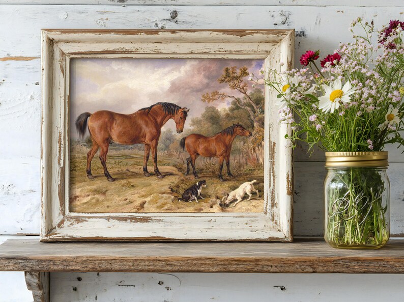 A framed painting of two brown horses with three dogs in a pastoral scene stands on a rustic shelf. Next to it is a mason jar filled with colorful wildflowers.