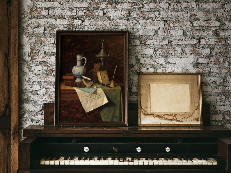 A vintage-style, dark wood, upright piano with a white and black keyboard. The piano is decorated with two framed pictures, one with a still life of a pitcher, a lamp, and a scroll, and the other with a blank white space.