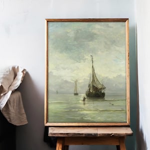 Framed painting on an easel depicting a serene seascape with sailing ships under a cloudy sky. Soft colors and textured brushstrokes create a calm, nostalgic mood.