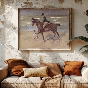 A cozy living room features a textured wall with a beach painting of a rider on horseback. A white sofa with brown pillows adds warmth and relaxation.