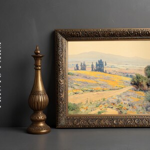Framed landscape painting of a rolling countryside with yellow flowers and distant trees, next to an intricately carved bronze vase on a gray background.