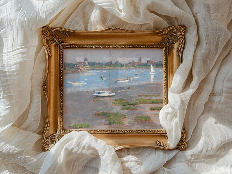 A framed painting of a serene harbor with sailboats on calm water, surrounded by a soft white fabric. The scene conveys tranquility and elegance.