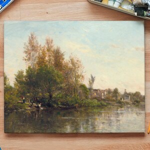 An oil painting depicting a serene landscape with a river, trees, and a distant village. The artwork features a palette of greens, browns, and blues, with reflections in the water. Paintbrushes and paint trays are visible.