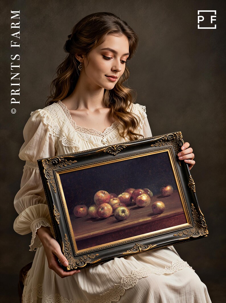 A woman in a vintage white dress holds a framed still-life painting of apples. The setting has a classic, elegant tone with soft lighting.