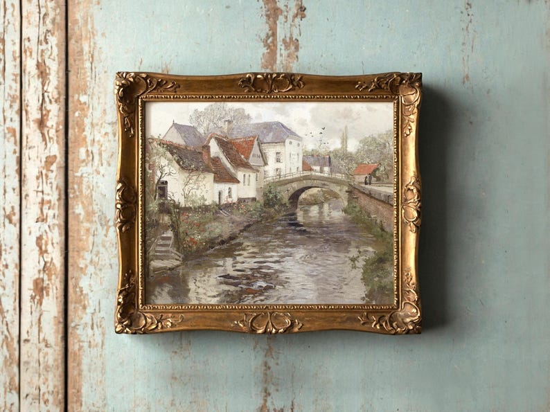 Framed painting of a serene village scene with a stone bridge over a river, surrounded by quaint houses and soft greenery, exuding a tranquil ambiance.
