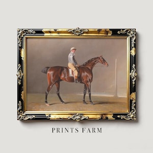 Framed painting of a jockey on a brown horse in a black and gold ornate frame. Neutral background with "PRINTS FARM" text below. Classic, elegant tone.