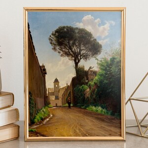 Framed painting of a serene landscape features a winding path, tall tree, and distant church under a blue sky with fluffy clouds. Peaceful ambiance.