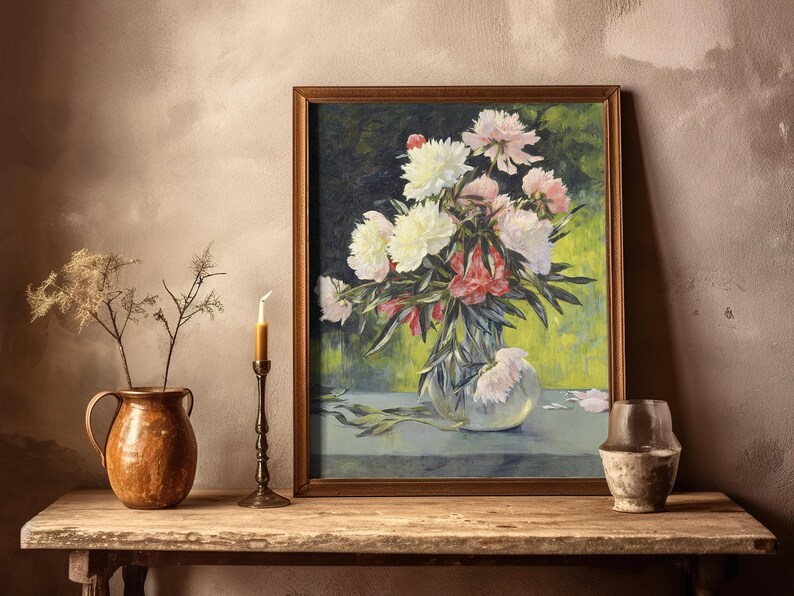A framed painting of vibrant peonies in a vase, set on a rustic wooden table with a copper pot, dried flowers, a candle, and an aged ceramic jar.