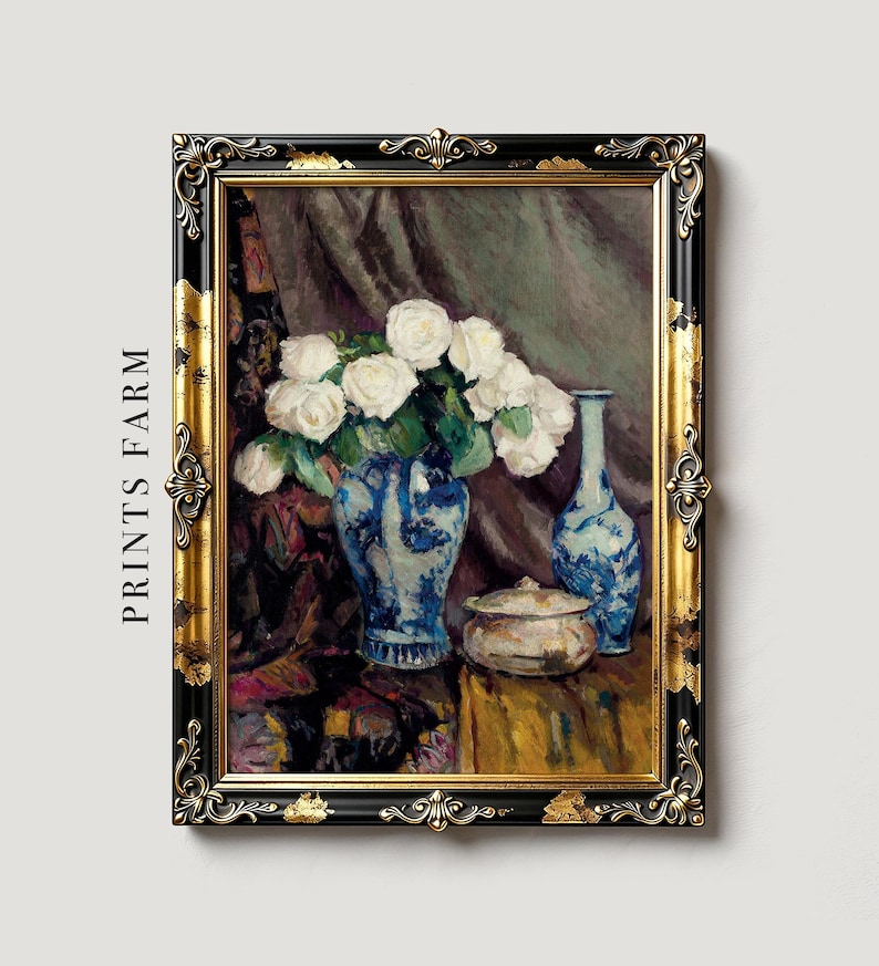 Framed painting of white roses in a blue vase, accompanied by a matching blue bottle and a small dish, set against a draped fabric background.