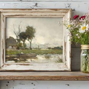 Framed landscape painting of a serene lake with trees and a cottage, next to a jar of wildflowers on a rustic wooden shelf, creating a tranquil, rustic vibe.