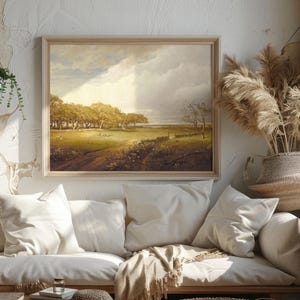 Cozy living room with a white sofa adorned with soft pillows and blankets beneath a landscape painting. Sunlight filters through, highlighting pampas grass decor.