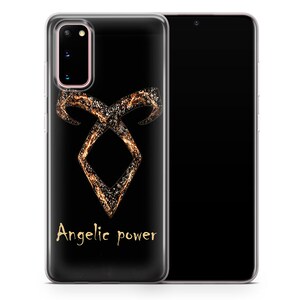 May include: A clear phone case with a black background and a gold angelic power symbol. The symbol is made up of a series of lines and dots that create a swirling effect. The text "Angelic power" is written in gold below the symbol.