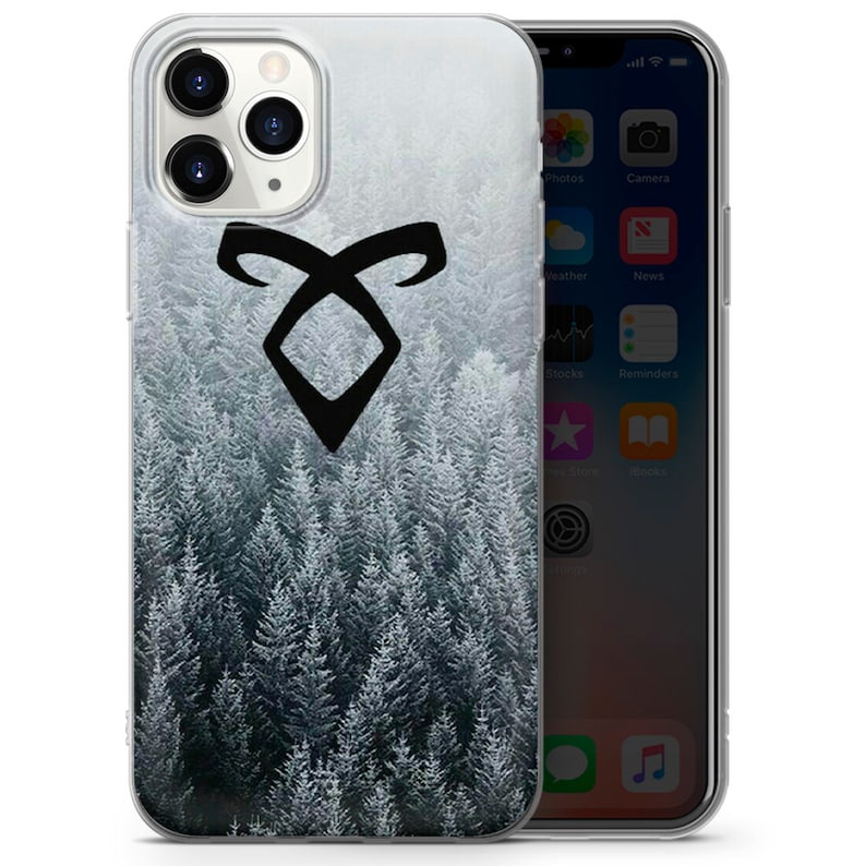May include: A clear phone case with a black symbol and a snowy forest background. The symbol is a stylized rune with two curved lines forming a diamond shape.