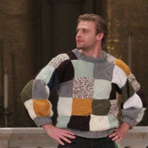 Könnte beinhalten: Ein Mann trägt einen mehrfarbigen Patchwork-Pullover und eine dunkelblaue Jeans mit Patchwork-Details. Die Jeans hat einen weißen, grünen und orangen Patch am linken Bein und einen weißen Patch am rechten Bein.