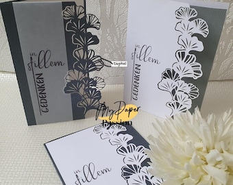 May include: Three white cards with black text and a black and white ginkgo leaf design. The text on the cards reads "in stillem Gedenken".