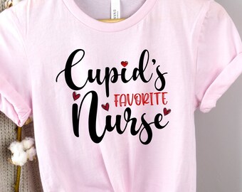 May include: Pink t-shirt with the text "Cupid's Favorite Nurse" in black lettering with red hearts.