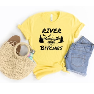 May include: Yellow t-shirt with a black graphic of a mountain scene and the text "River Bitches".