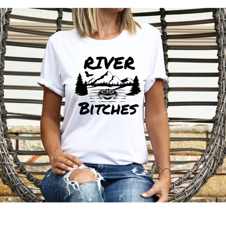May include: White t-shirt with black text that reads "River Bitches". The text is surrounded by a graphic of a mountain range, trees, and a boat on a river.