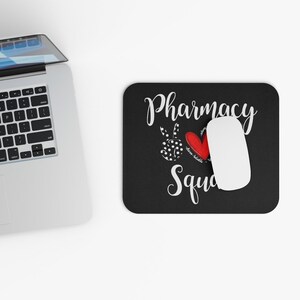 May include: Black mouse pad with white text that reads "Pharmacy Squad" with a red heart and a peace sign with white polka dots.