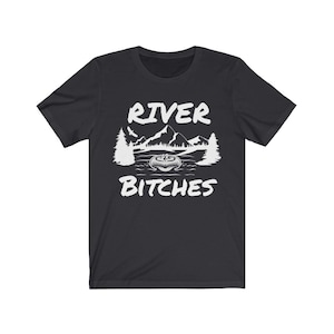 Pu&ograve; includere: T-shirt nero con un design grafico bianco di una scena di montagna con il testo "River Bitches".