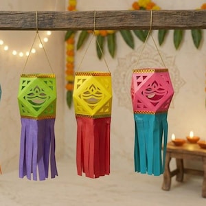 May include: Five hanging paper lanterns in vibrant colors, each featuring a geometric cutout design of a diya lamp on the sides and long, thin paper fringe at the bottom. The lanterns are suspended by thin gold wires from a horizontal wooden beam.