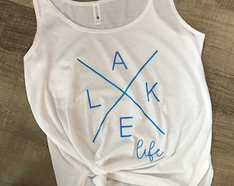 May include: White tank top with a blue graphic that says "Lake Life" with a stylised "A" and "K" forming an X.