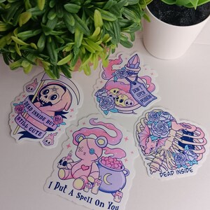 May include: Four stickers with a spooky, cute aesthetic. The stickers feature a pink and purple potion bottle with a skull and crossbones, a pink teddy bear with a cauldron, a skeleton with a bat and roses, and a grim reaper with a scythe and the text "Dead inside but still cute".