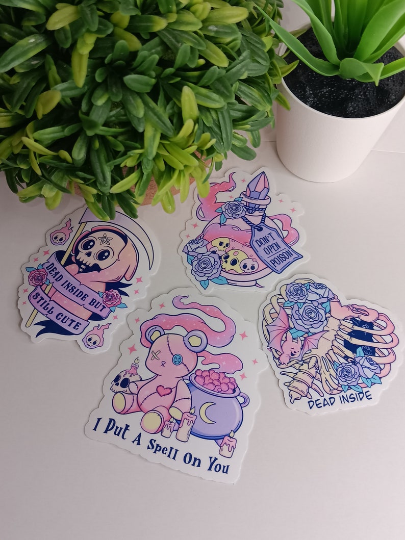 May include: Four stickers with a spooky, cute aesthetic. The stickers feature a pink and purple potion bottle with a skull and crossbones, a pink teddy bear with a cauldron, a skeleton with a bat and roses, and a grim reaper with a scythe and the text "Dead inside but still cute".