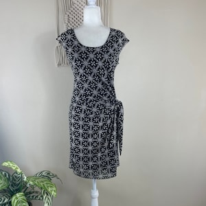 May include: A black and white patterned dress with a scoop neck and short sleeves. The dress has a tie at the waist.