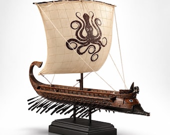 May include: A wooden model ship featuring a dark brown hull with multiple oars extending from the sides. The ship has a single off-white square sail decorated with a large brown octopus graphic. It is mounted on a black rectangular base stand.