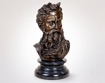 May include: A bronze bust sculpture of a bearded man with curly hair and a stern expression. The sculpture is mounted on a black marble pedestal. The bust features detailed facial features and a textured surface, showcasing the artist's skill.